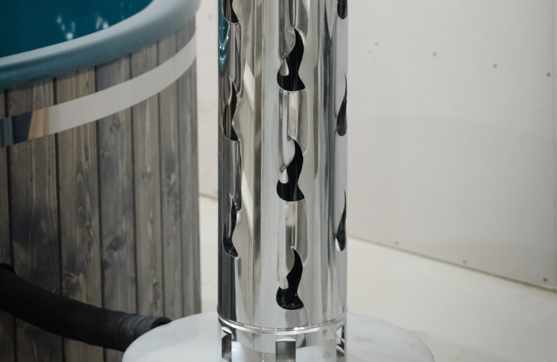 Detailansicht des Metallschornsteins des Feuerbad Hot Tubs DIANA, mit dekorativen Luftöffnungen, angeschlossen an den integrierten Metallofen und die Holzverkleidung des Hot Tubs