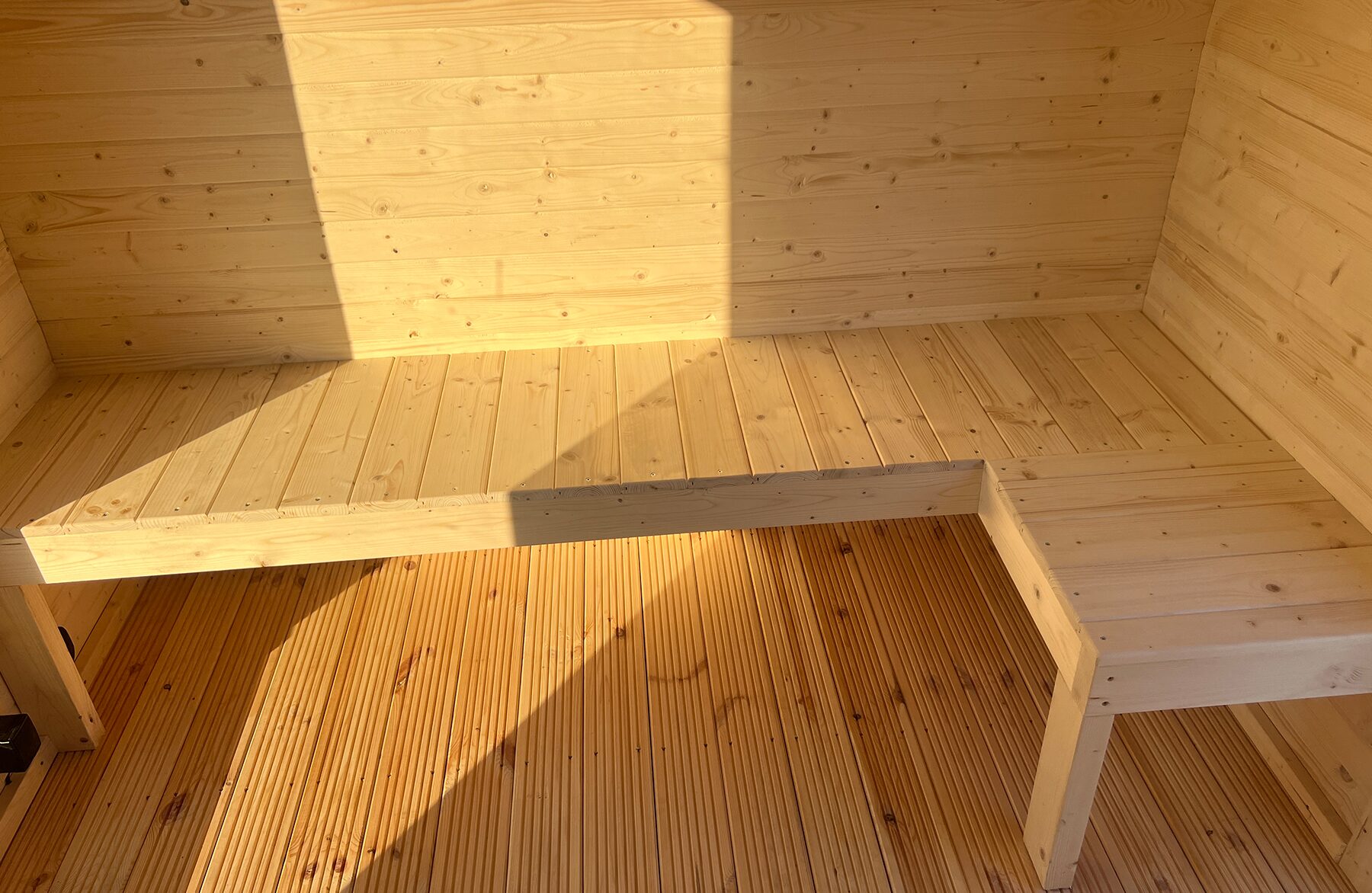Innenansicht der Feuerbad Sauna CERES mit heller Holzverkleidung und integrierter Sitzbank
