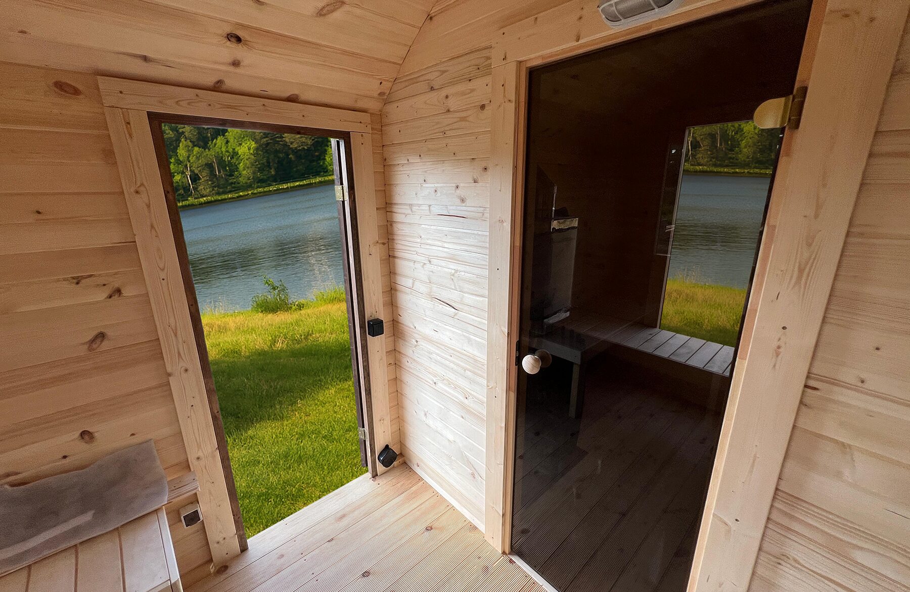 Innenansicht der Feuerbad Sauna CERES mit heller Holzverkleidung, integrierter Sitzbank und Glastür
