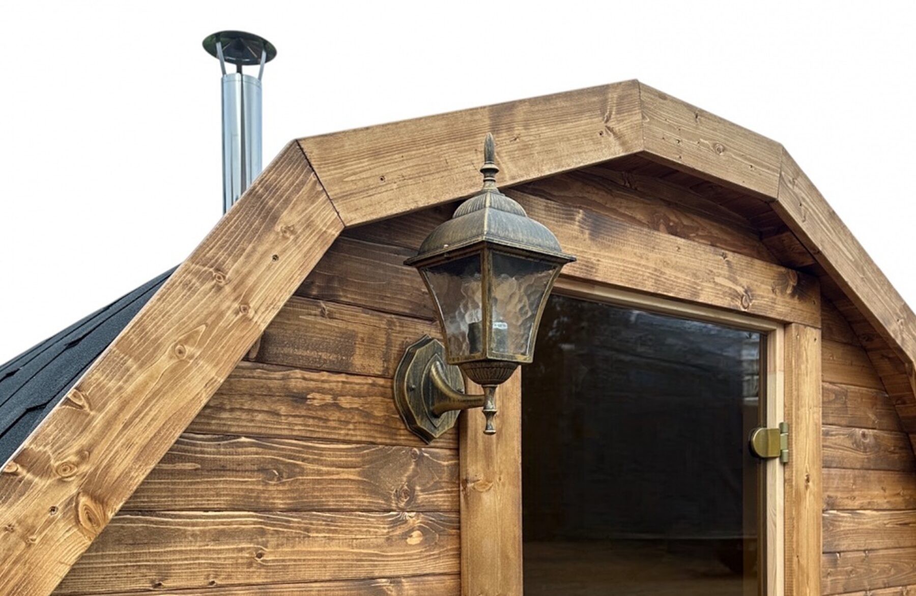 Detailansicht der Feuerbad Fass-Sauna JUNO mit rustikaler Holzverkleidung, Glastür, dekorativer Außenlampe und sichtbarem Schornstein, freigestellt vor hellem Hintergrund